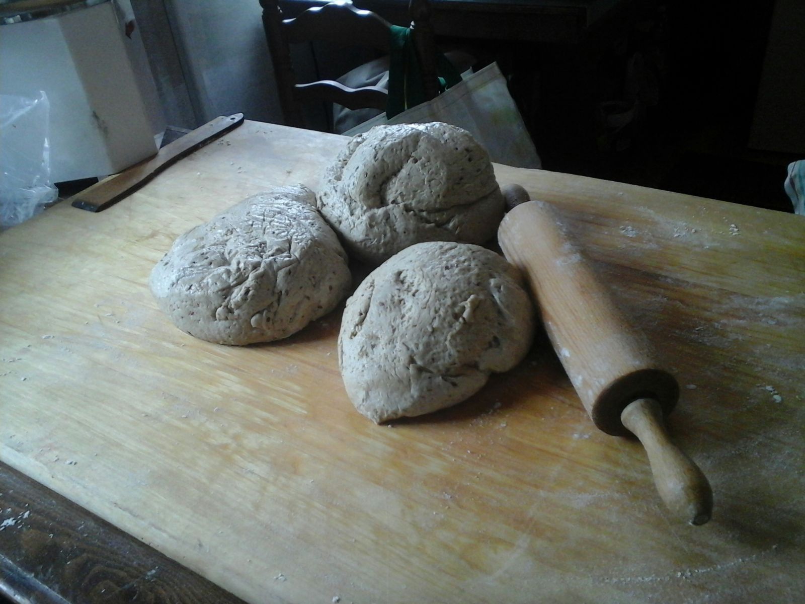 Tres bolas de masa y un rodillo sobre una tabla de cortar