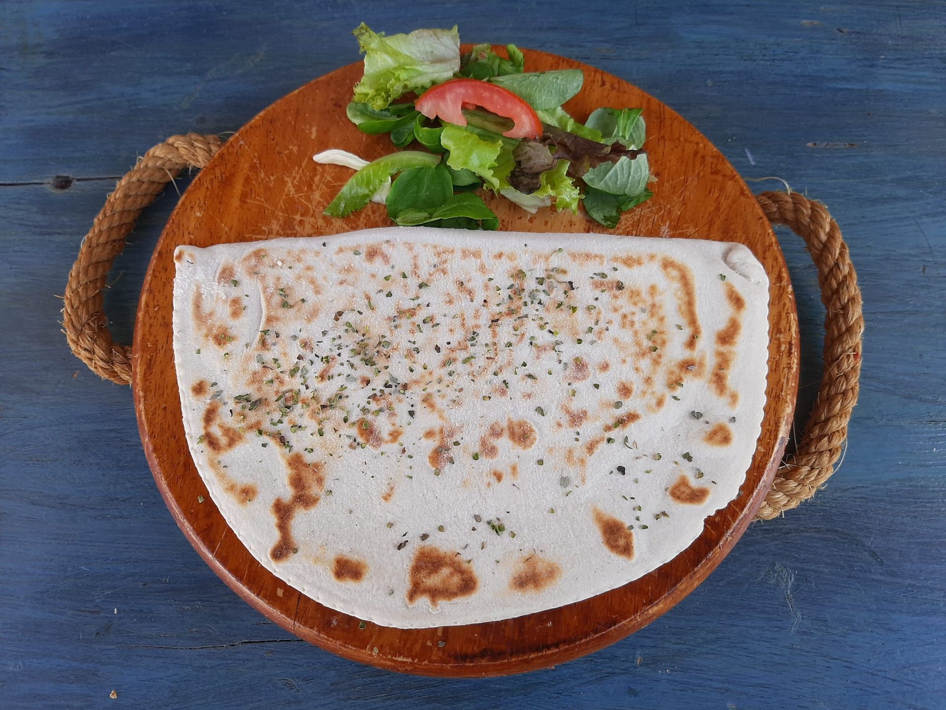 Una tortilla con una ensalada encima sobre una tabla de cortar de madera.