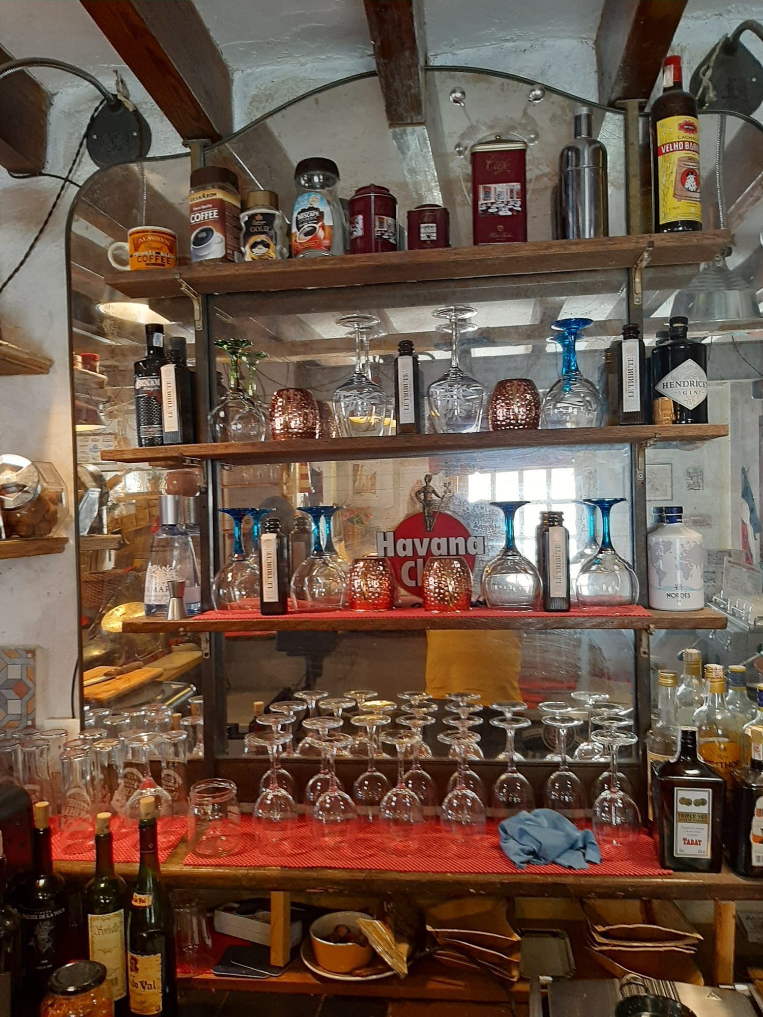 Un estante lleno de copas y botellas de vino con una camiseta roja que dice La Habana.