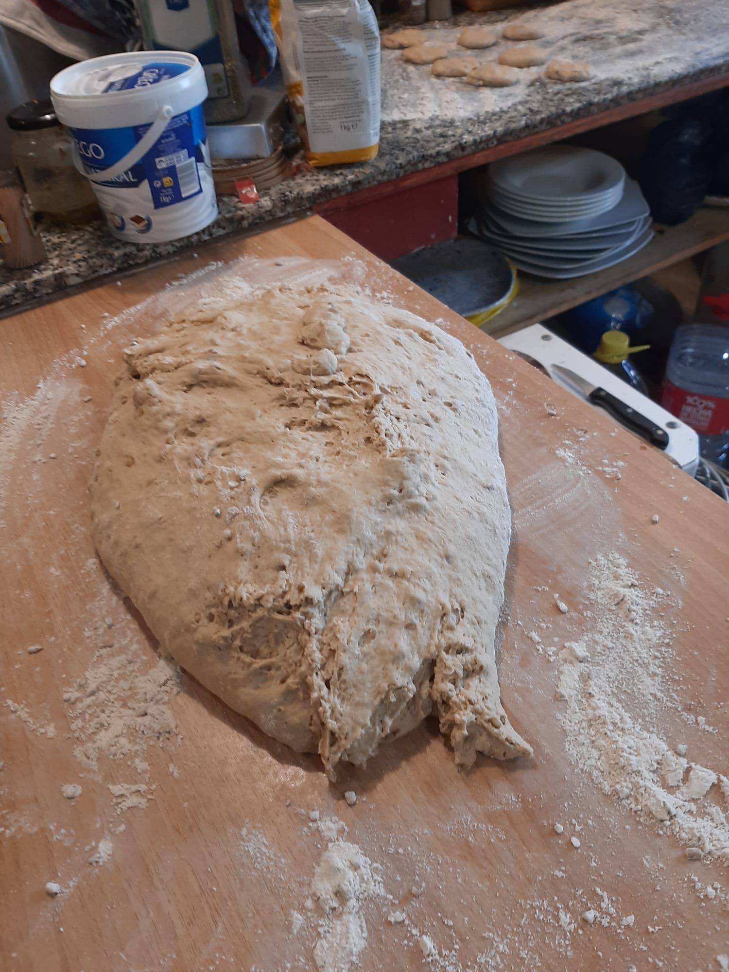 Un gran trozo de masa reposa sobre una tabla de cortar de madera.