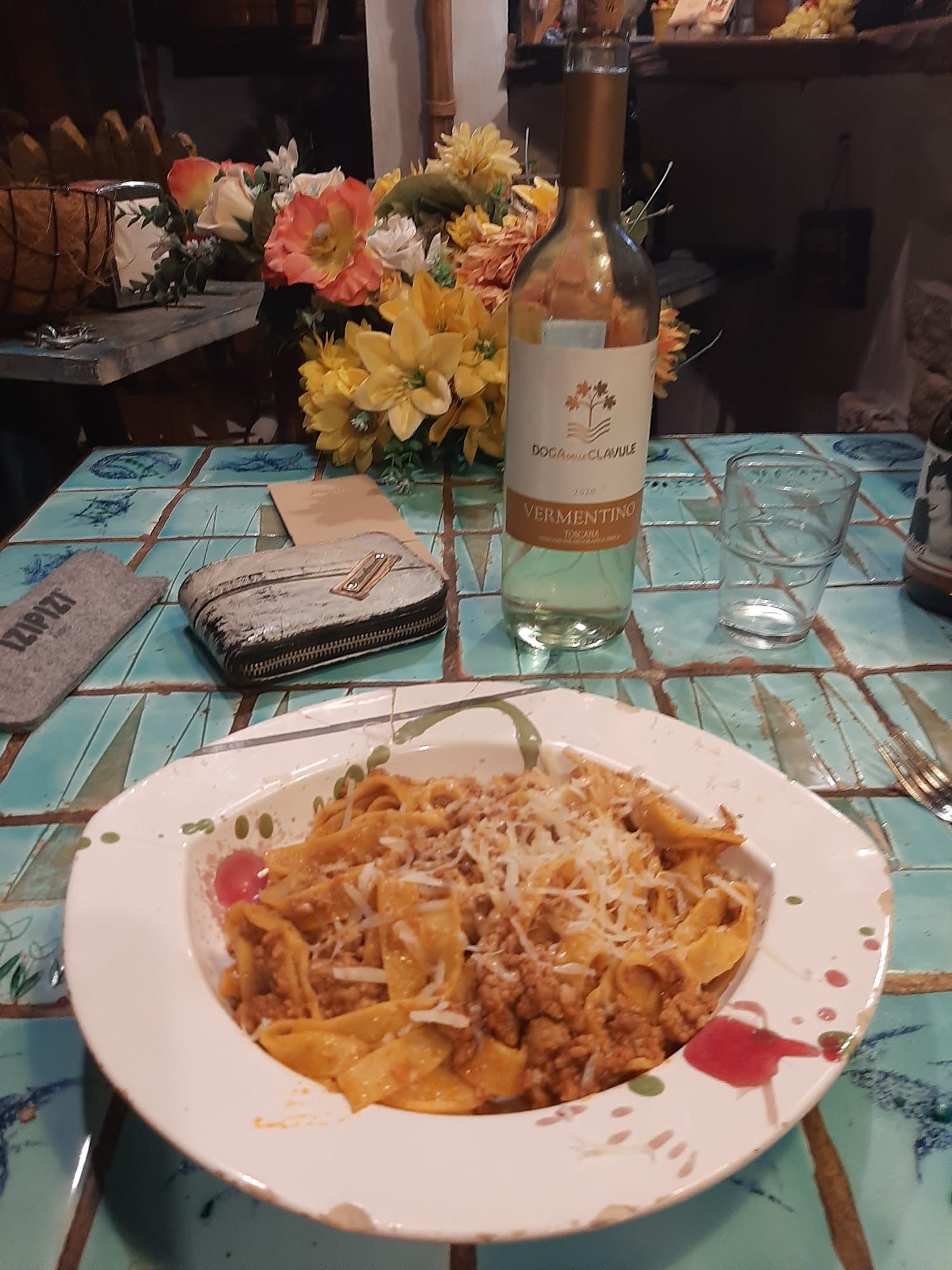 Un plato de pasta está en una mesa al lado de una botella de vino.