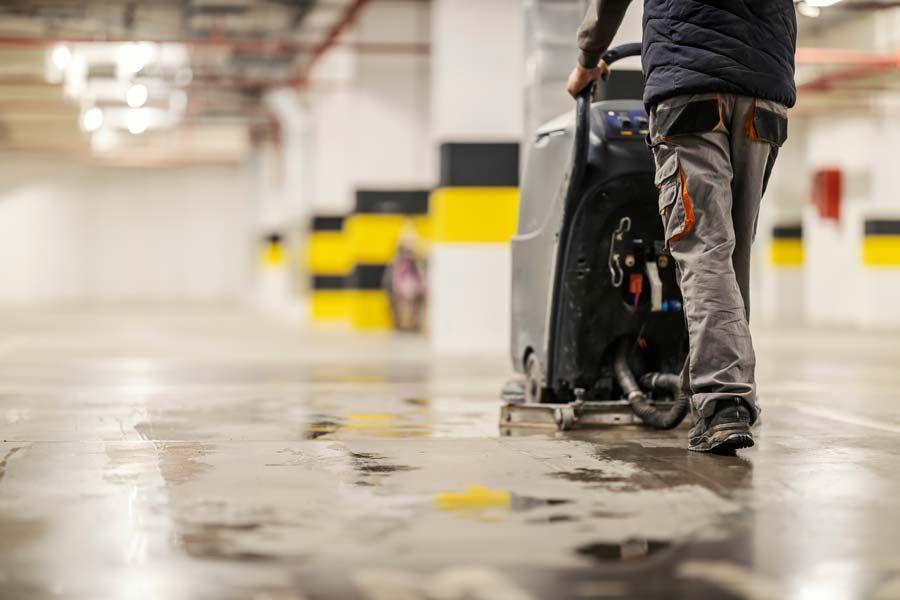 Technicien qui passe une autolaveuse dans un parking