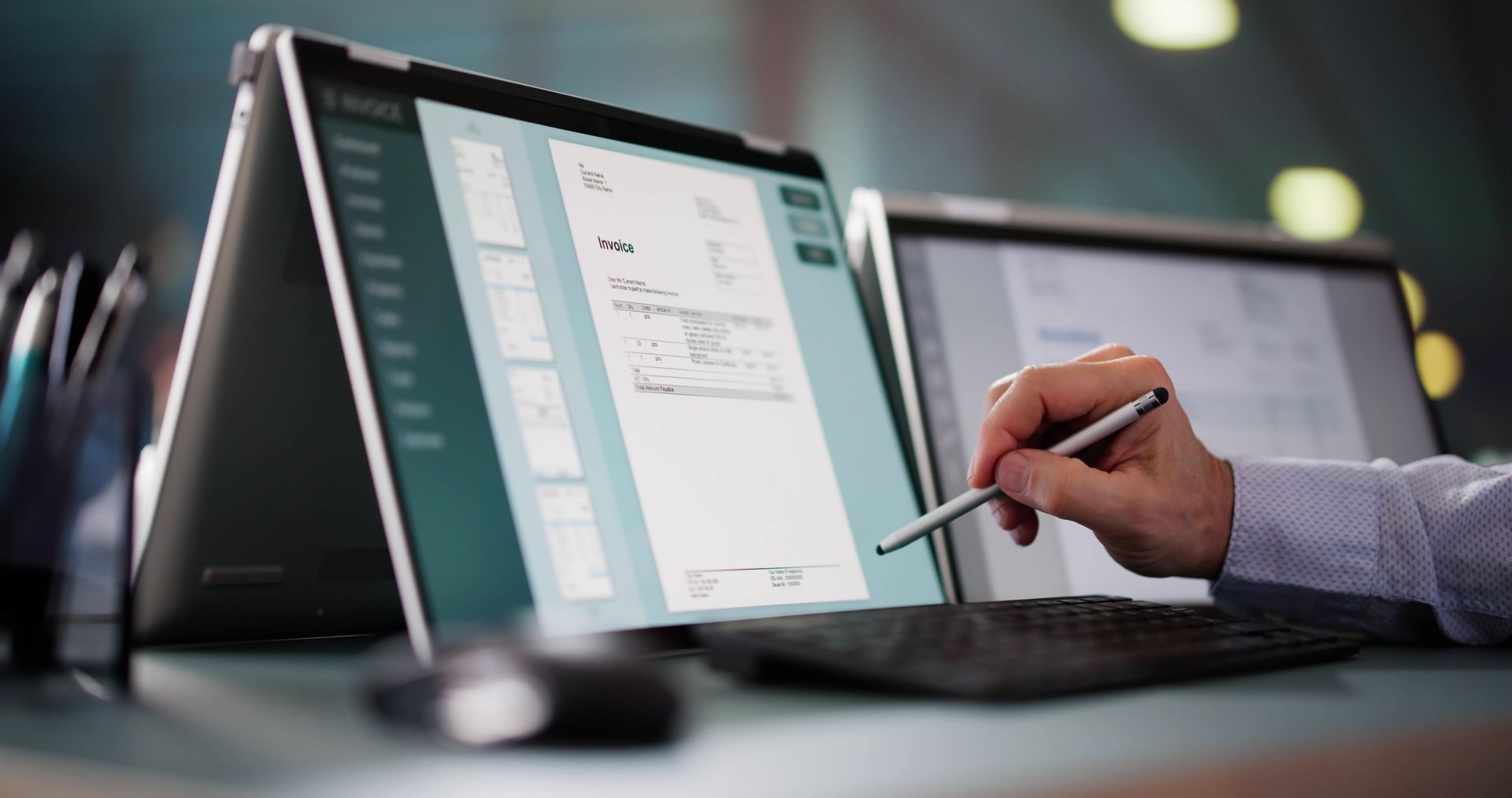 Une main tenant un stylet pour utiliser une tablette dans un espace de travail.
