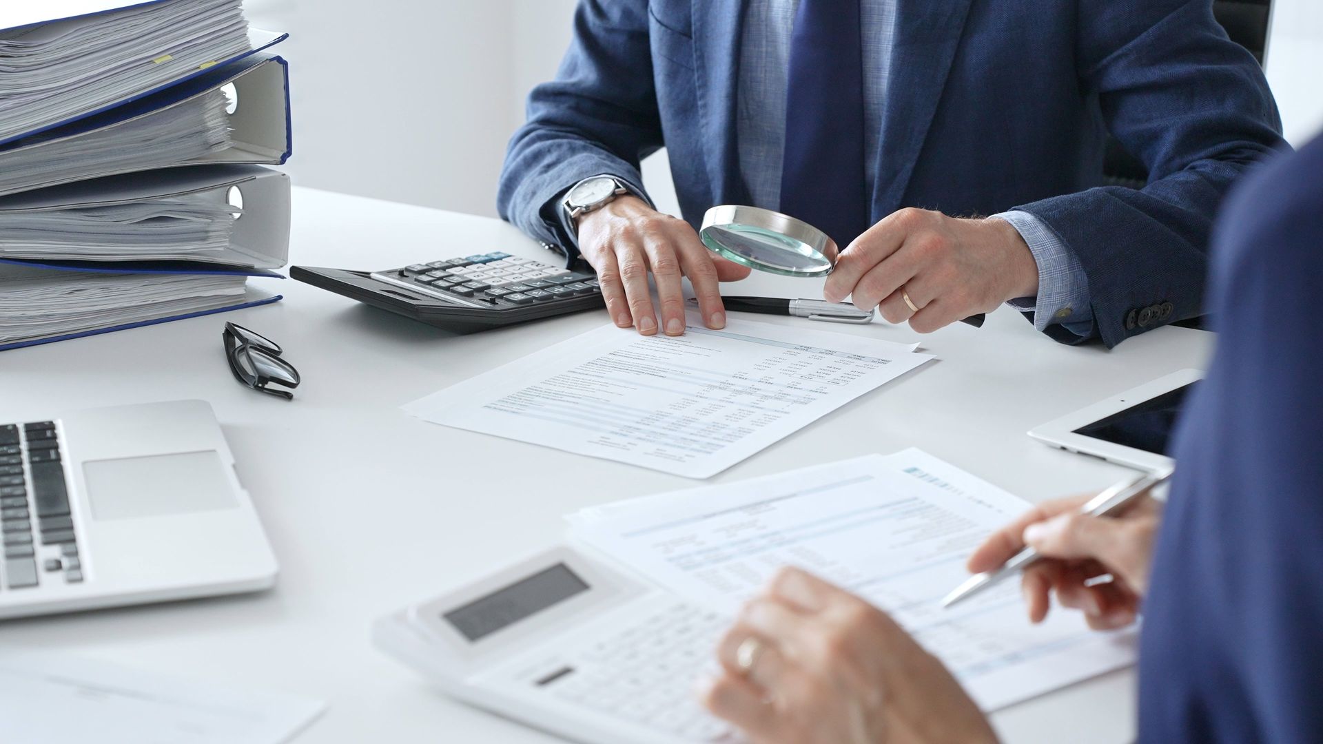 Des personnes travaillant à un bureau avec des documents, une calculatrice et un ordinateur portable.