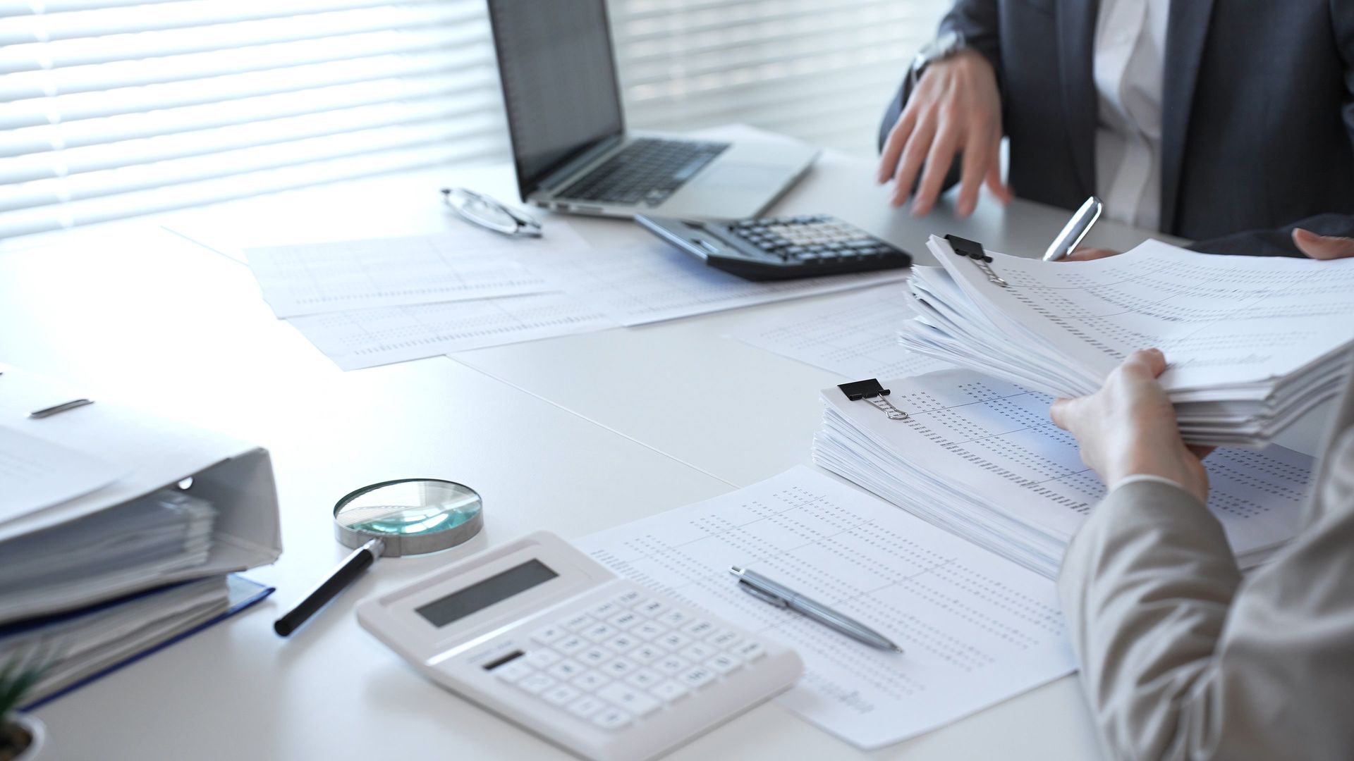 Des personnes examinent des documents financiers, munies de calculatrices.