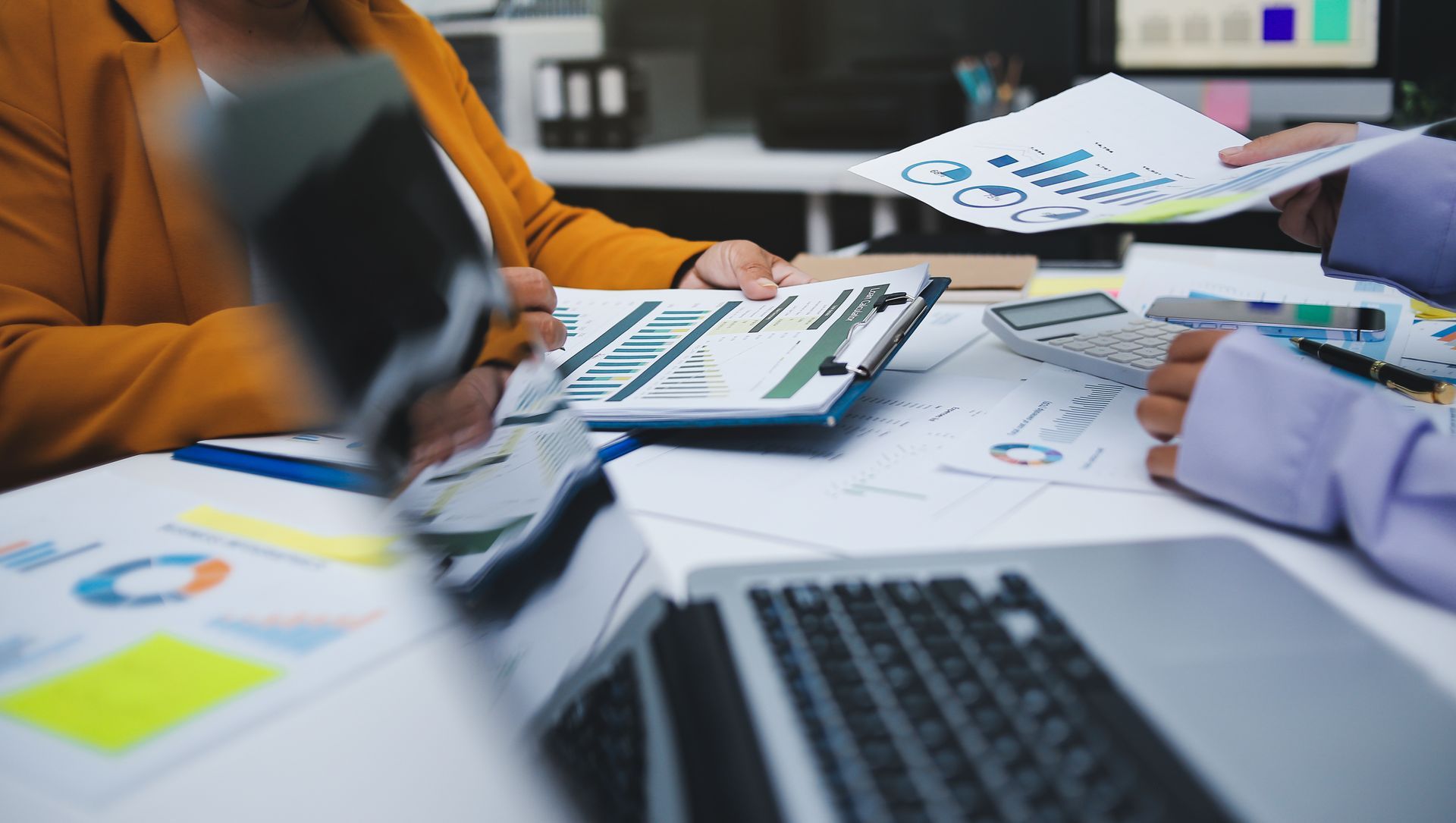 Réunion d'affaires avec des documents, des graphiques et un ordinateur portable sur une table.