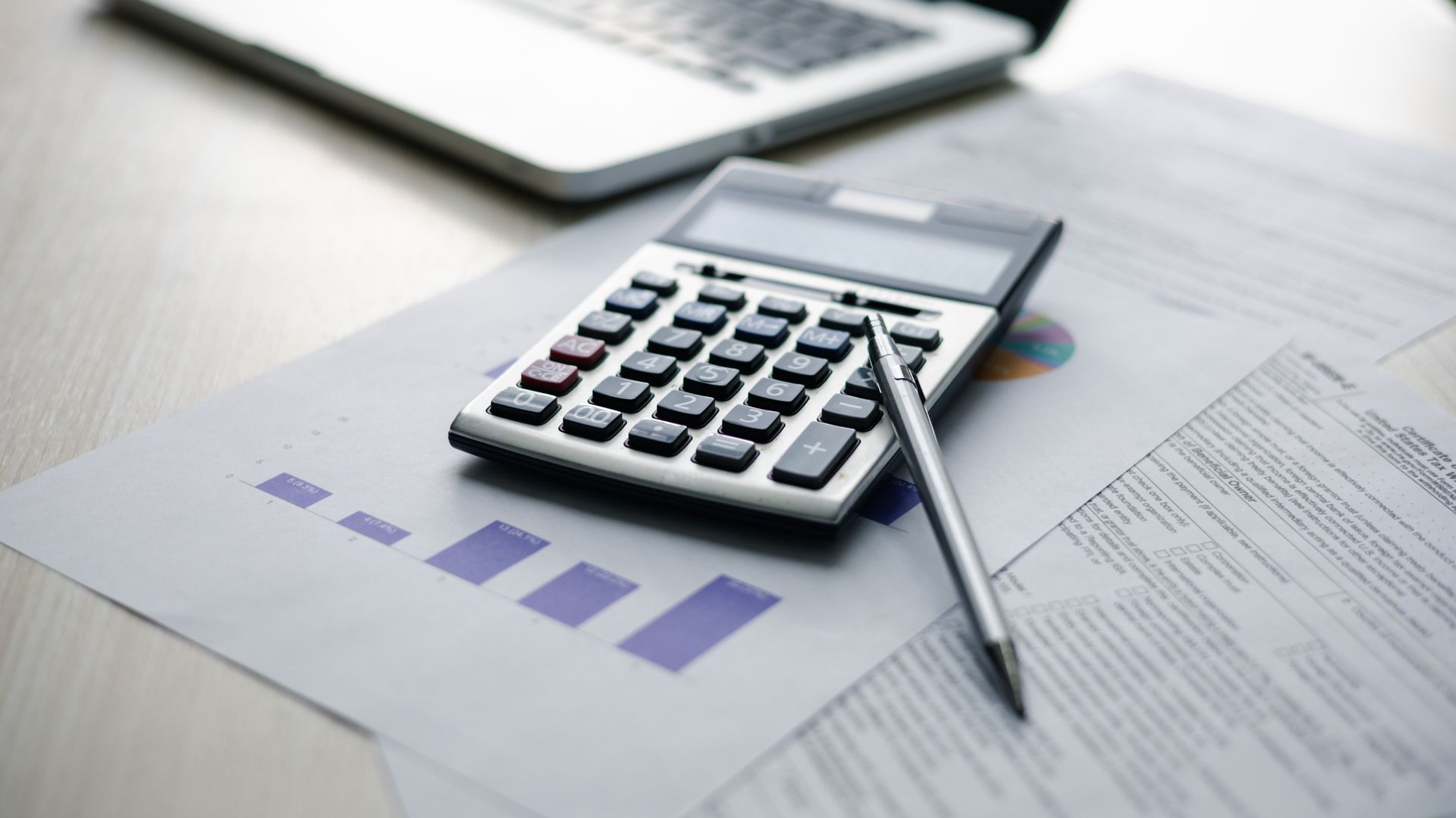 Une calculatrice, un crayon et un document comptable posés sur un bureau.