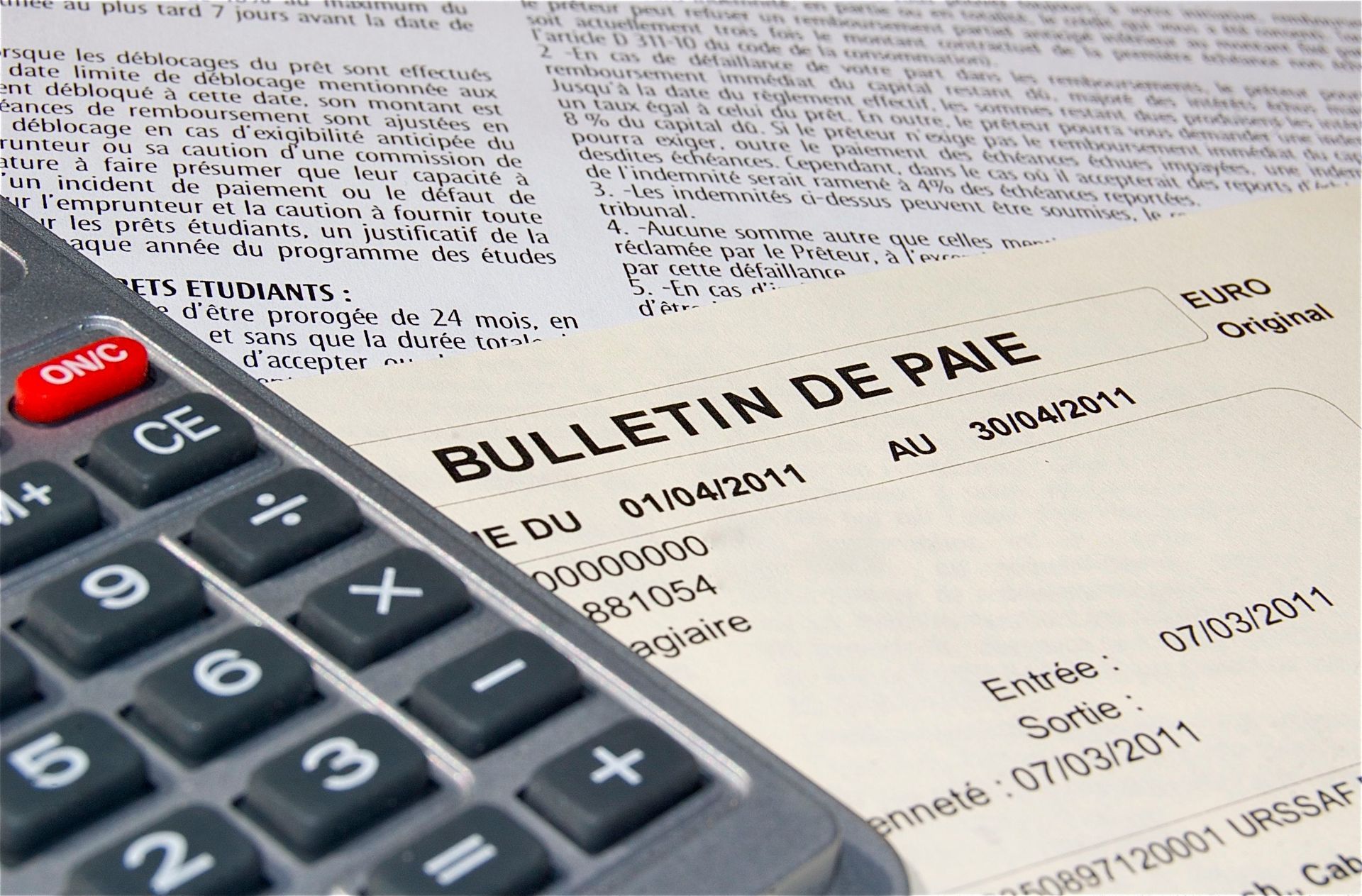 Calculatrice posée sur un bulletin de paie français avec détails visibles des impôts et des déductions.