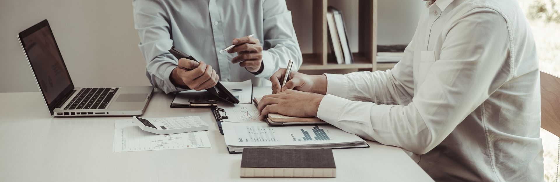 Deux personnes dans un bureau lumineux discutent et prennent des notes.
