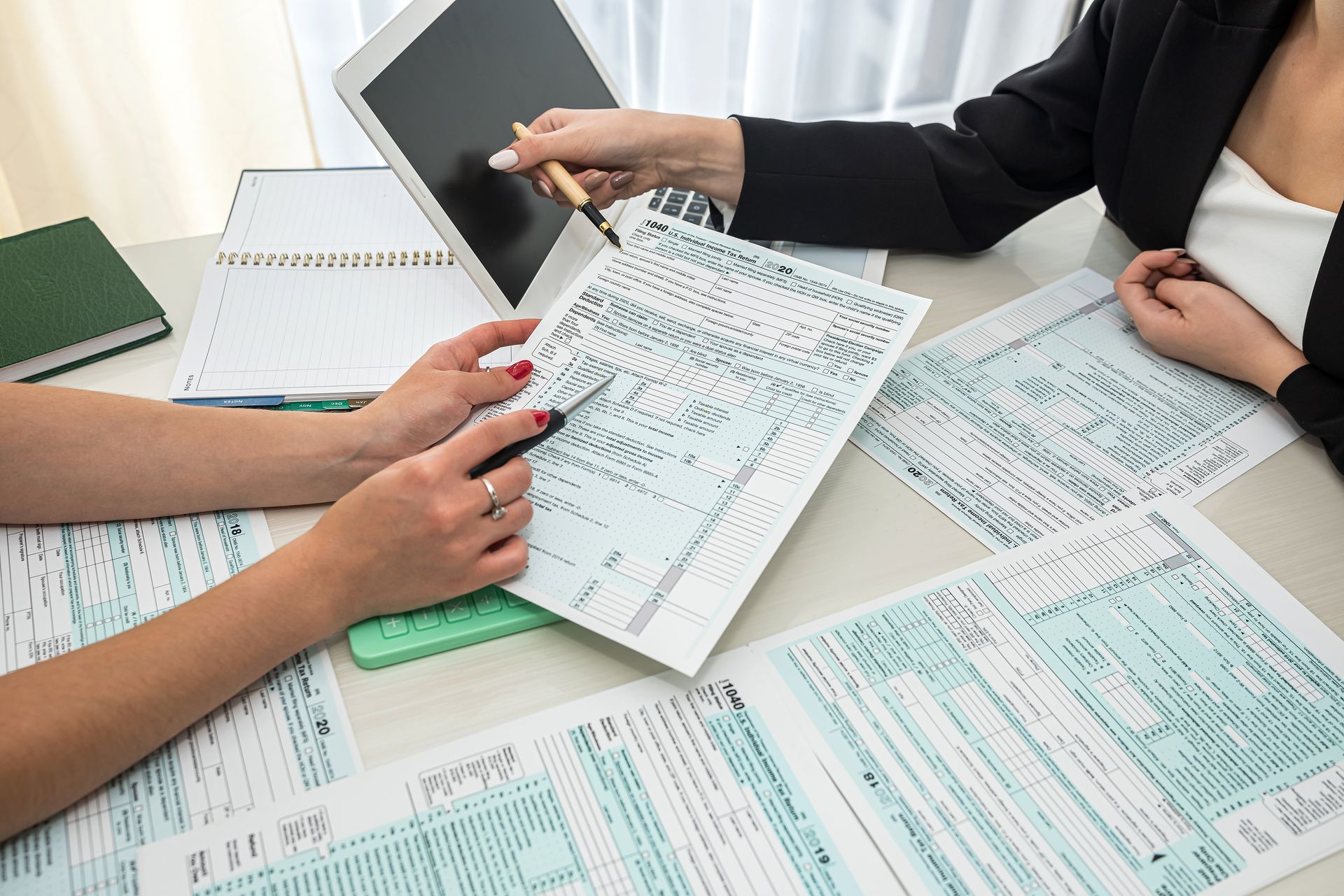 Des personnes examinent des documents à un bureau, avec des formulaires et un ordinateur portable.