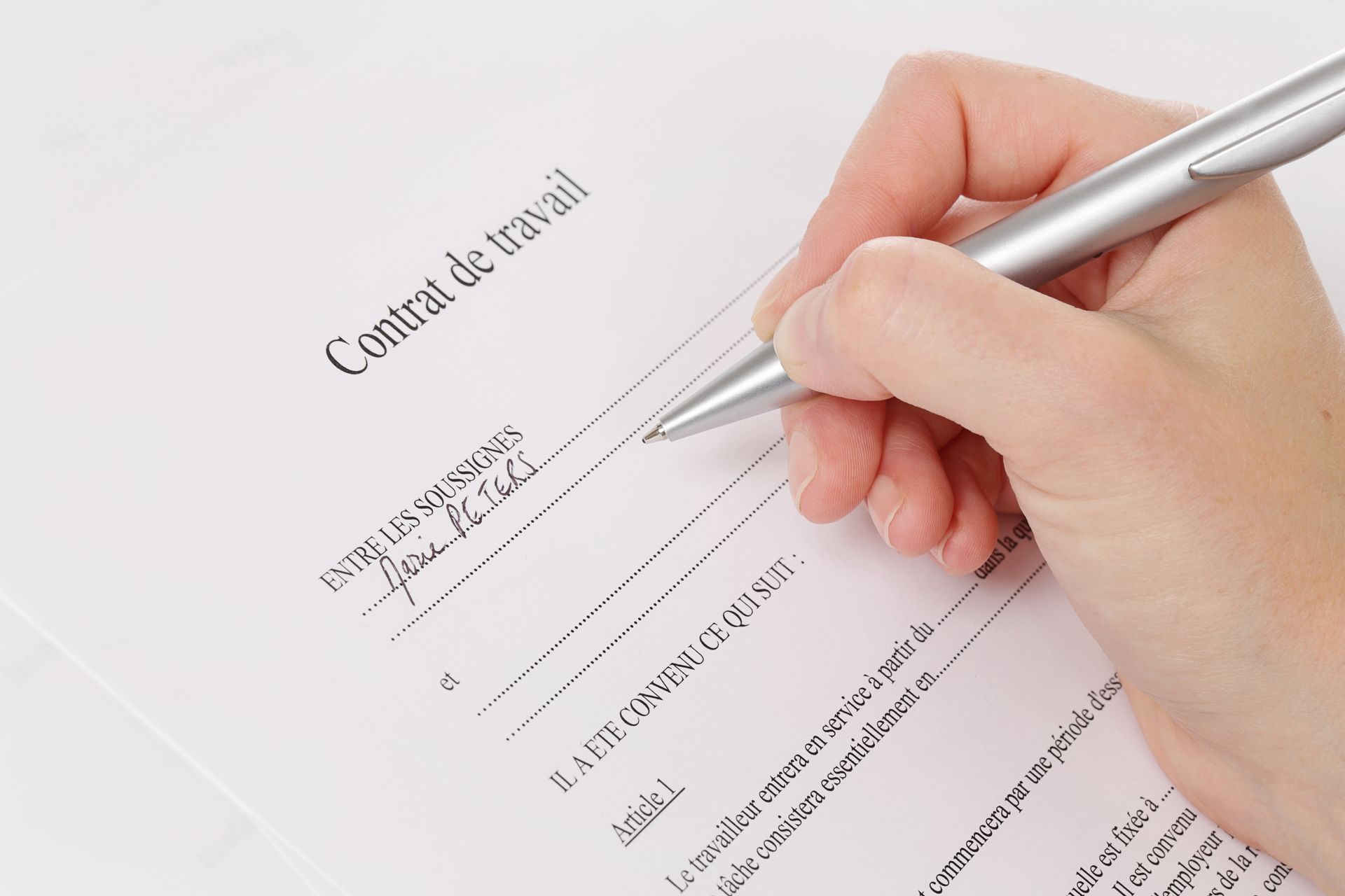 Signature manuscrite d'un contrat de travail avec un stylo argenté.