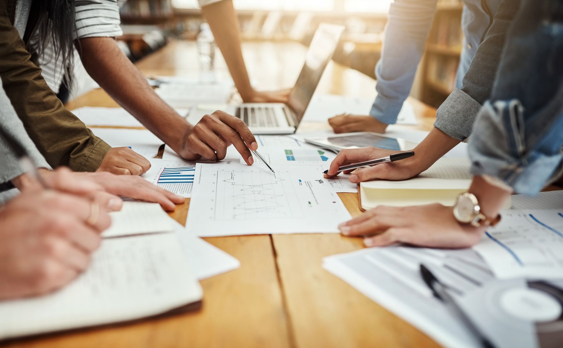 Des personnes qui collaborent sur des documents et des ordinateurs portables autour d'une table de réunion.
