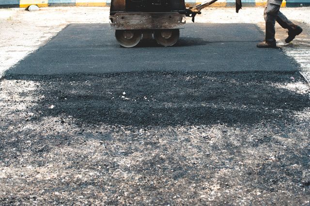 Rouleau compresseur passant sur du goudron frais lors de travaux de voirie