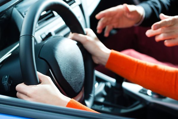 Une personne tenant le volant d'une voiture.