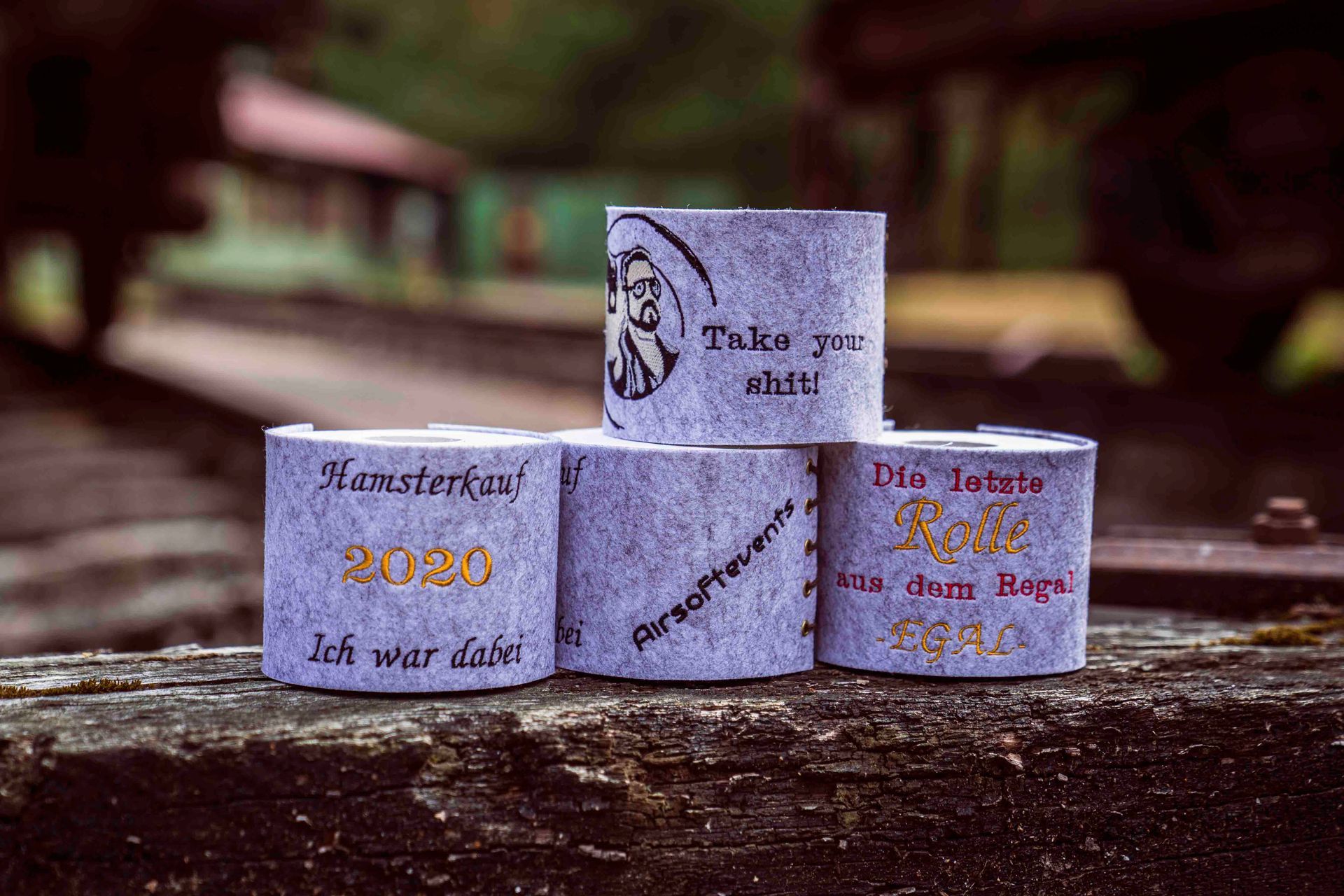 Fünf dekorative Zylinder mit deutscher Beschriftung und einem Porträt, auf Holz gestapelt