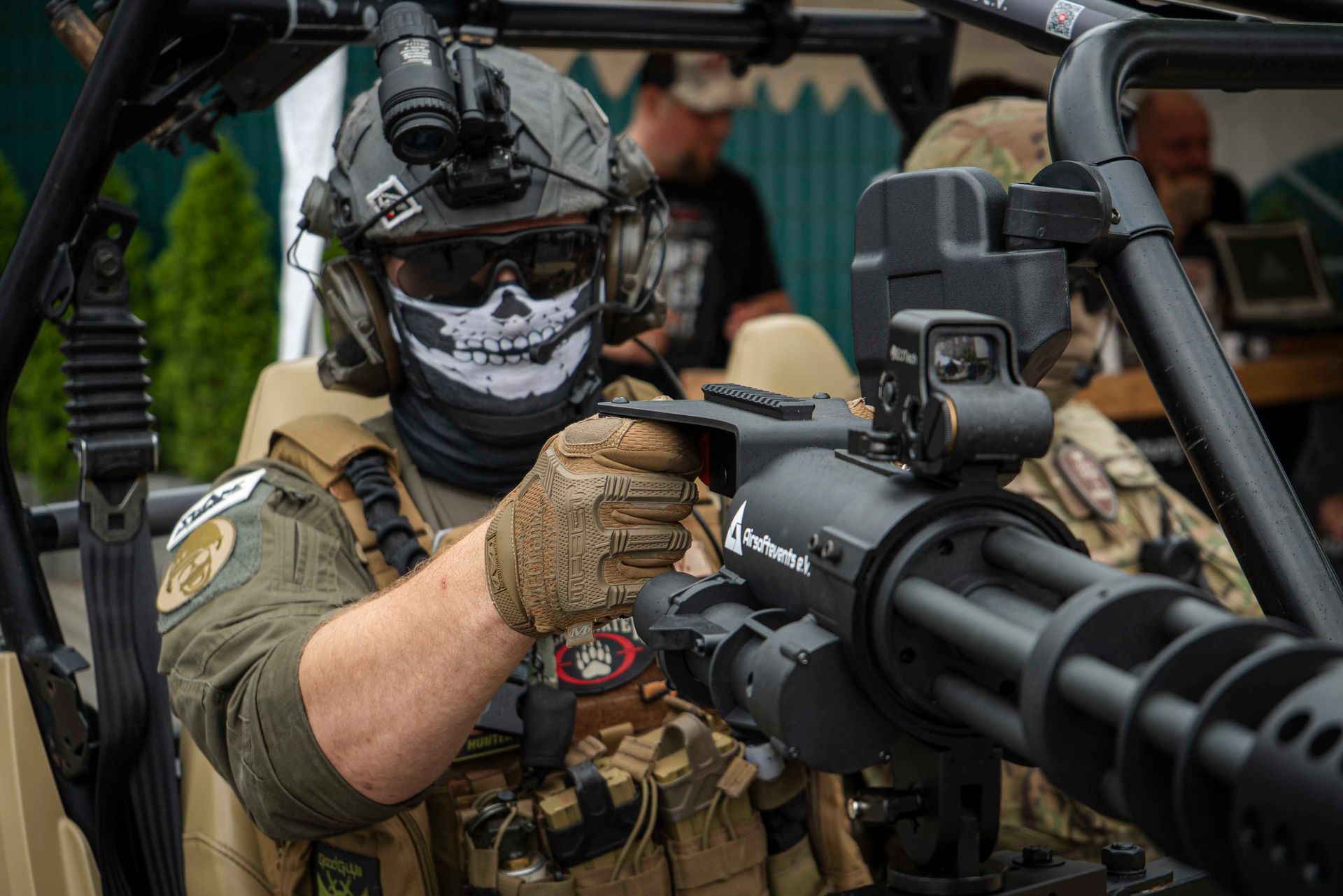 Eine Person in taktischer Ausrüstung bedient ein montiertes Gatling-Geschütz. Sie trägt eine Maske und ein Nachtsichtgerät 