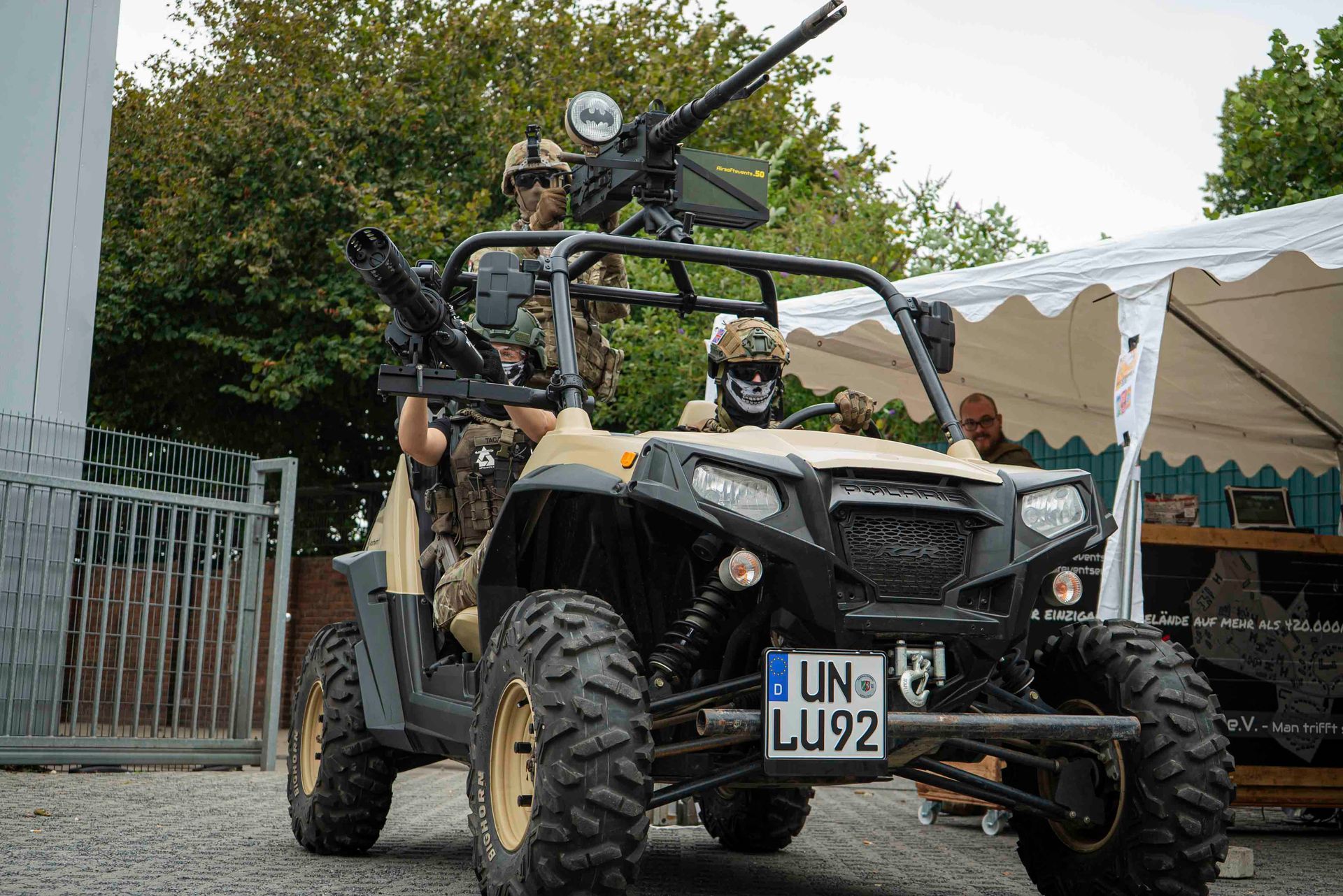 Soldaten in Militärkleidung auf einem beigen Geländewagen, bewaffnet mit Maschinengewehren