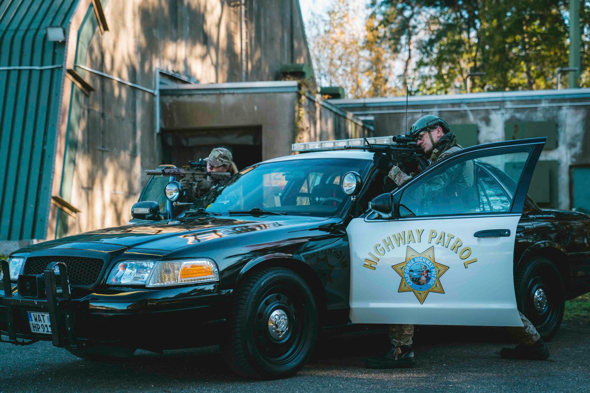 Zwei bewaffnete Polizisten stehen vor einem schwarz-weißen Streifenwagen der Autobahnpolizei, eine Tür ist geöffnet
