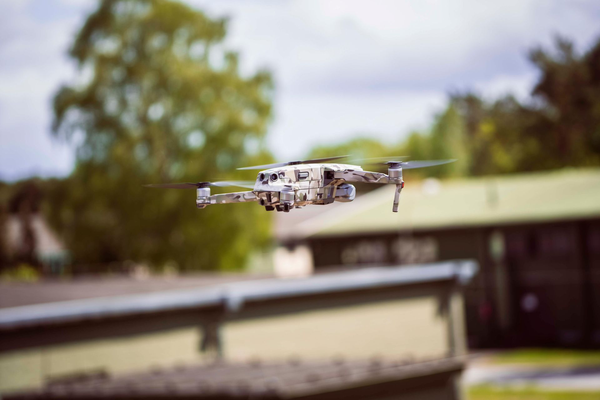 Drohne mit Tarnmuster fliegt in der Nähe eines Gebäudes.