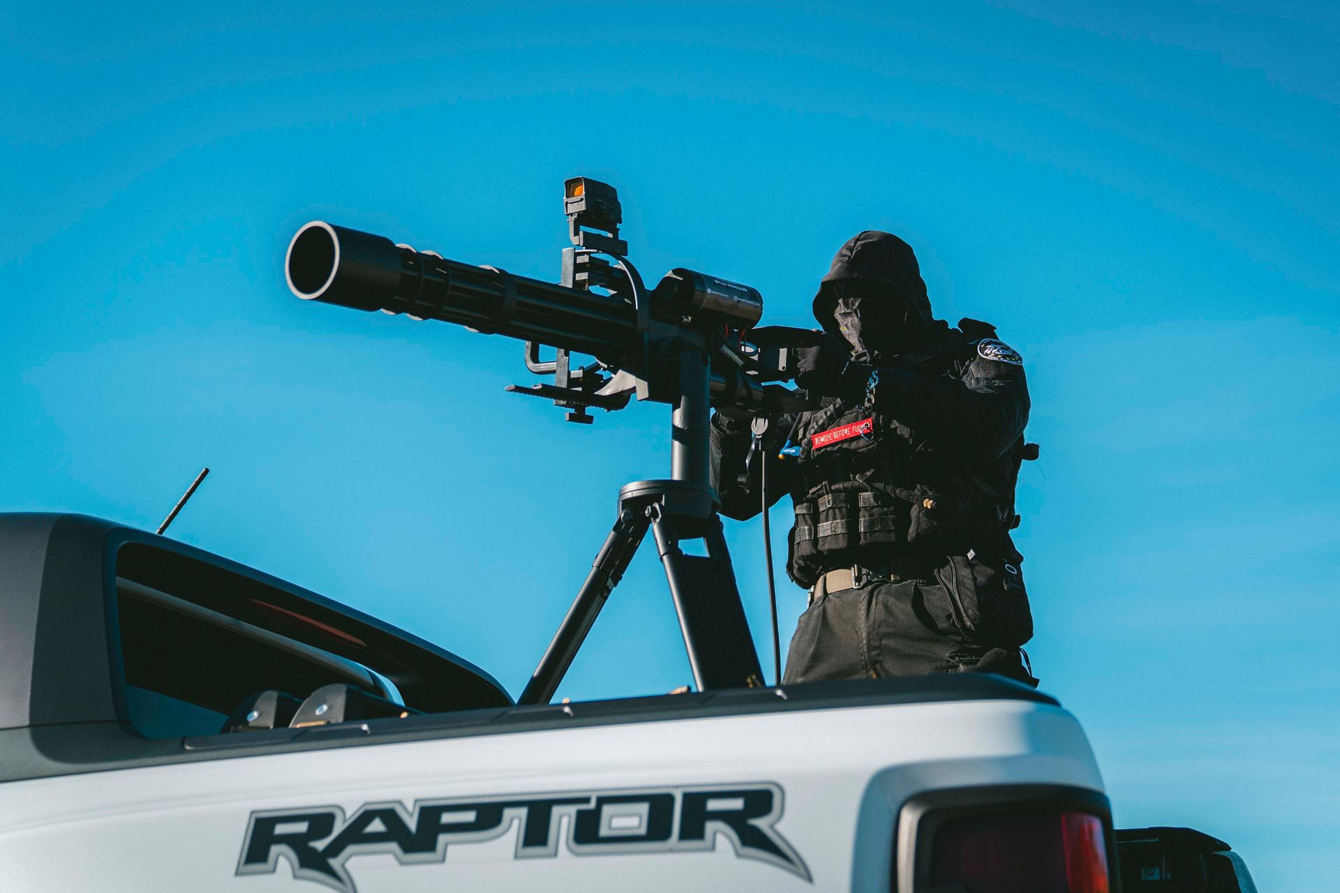 Eine Person in taktischer Ausrüstung zielt mit einer Waffe, die auf der Ladefläche eines Pickups montiert ist
