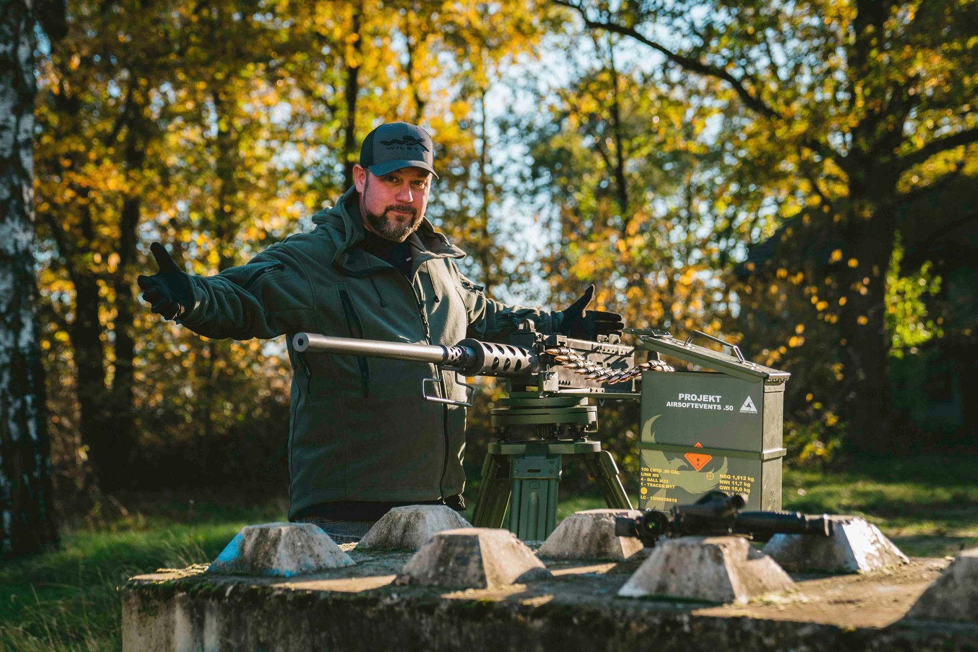 Ein Mann gestikuliert in der Nähe eines auf einem Dreibein montierten schweren Maschinengewehrs