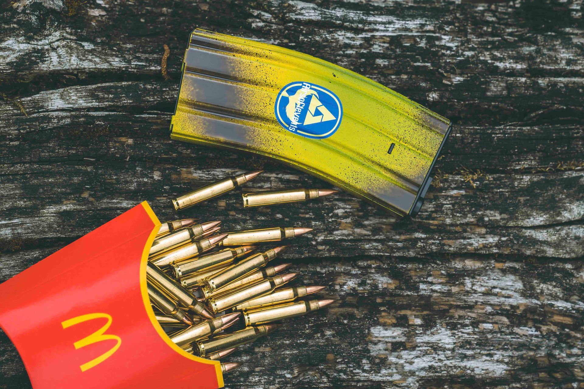 Eine mit Patronen gefüllte Pommes-Frites-Schachtel steht neben einem gelben, mit Graffiti besprühten Gegenstand 