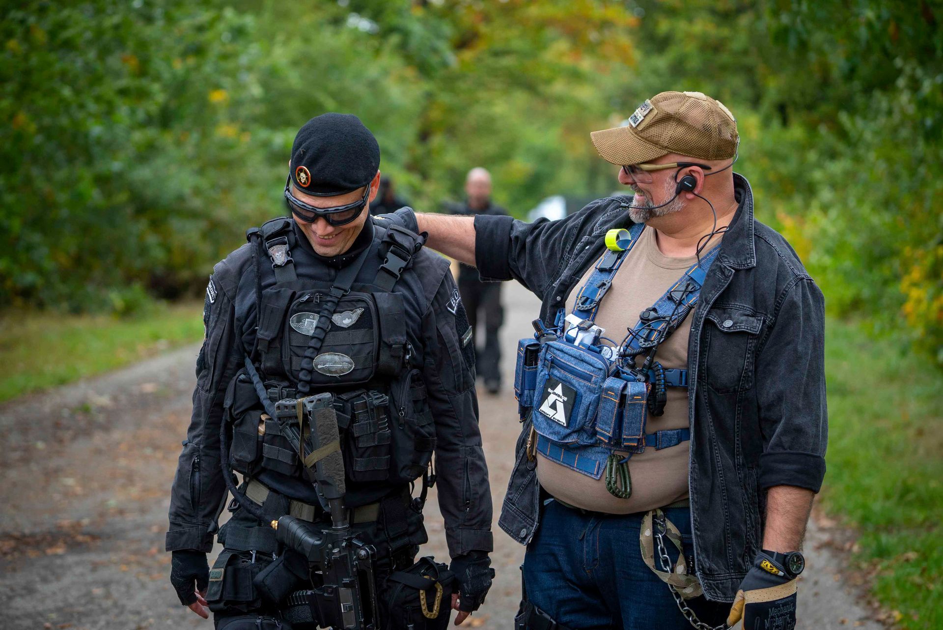Zwei Männer auf einem Pfad. Der eine trägt Ausrüstung, der andere Zivilkleidung und hat den Arm um den ersten gelegt