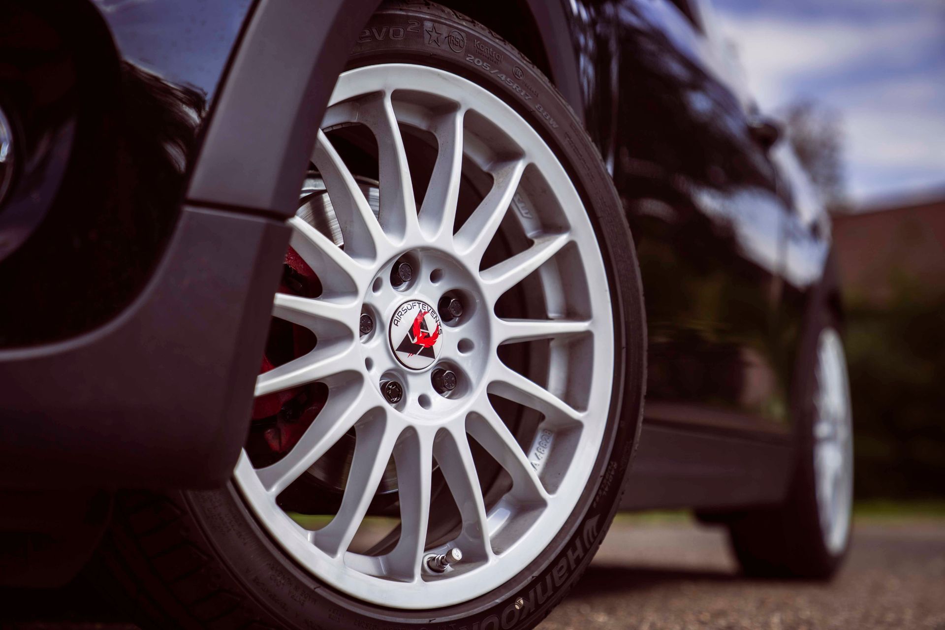 Silbernes Autorad mit schwarzem Reifen auf einem schwarzen Auto.