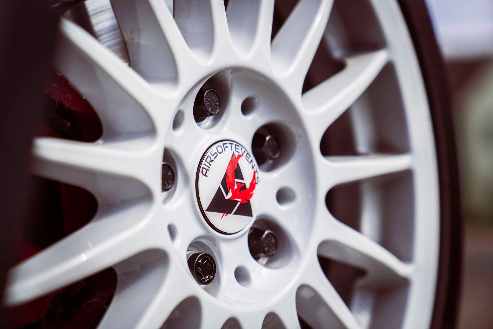 Weißes Autorad mit schwarzen Radmuttern und einem Logo in der Mitte.