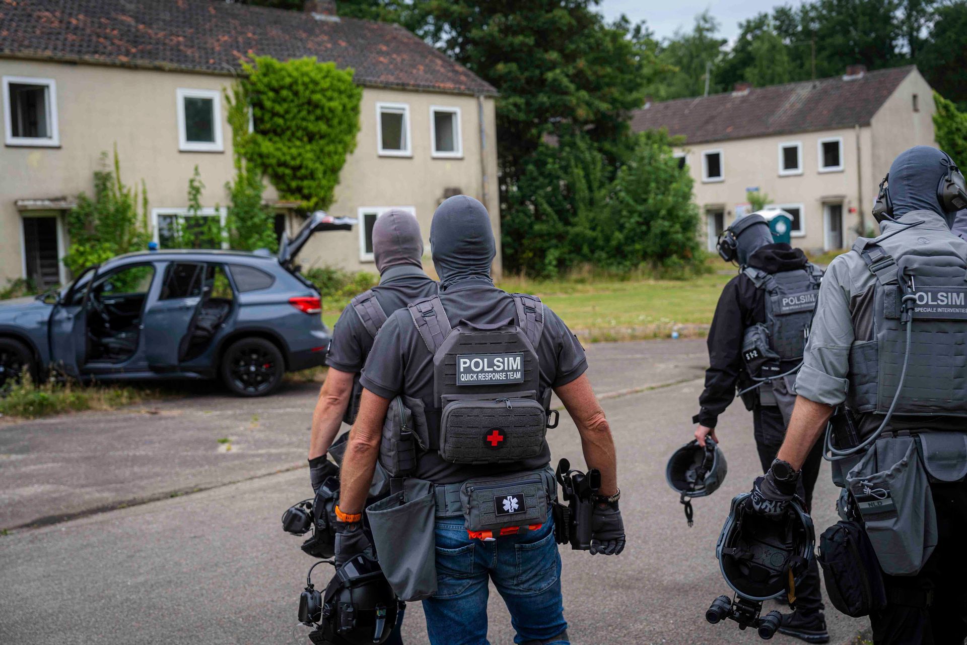 Bewaffnete Polizisten nähern sich einem Gebäude, einer von ihnen trägt einen Helm.