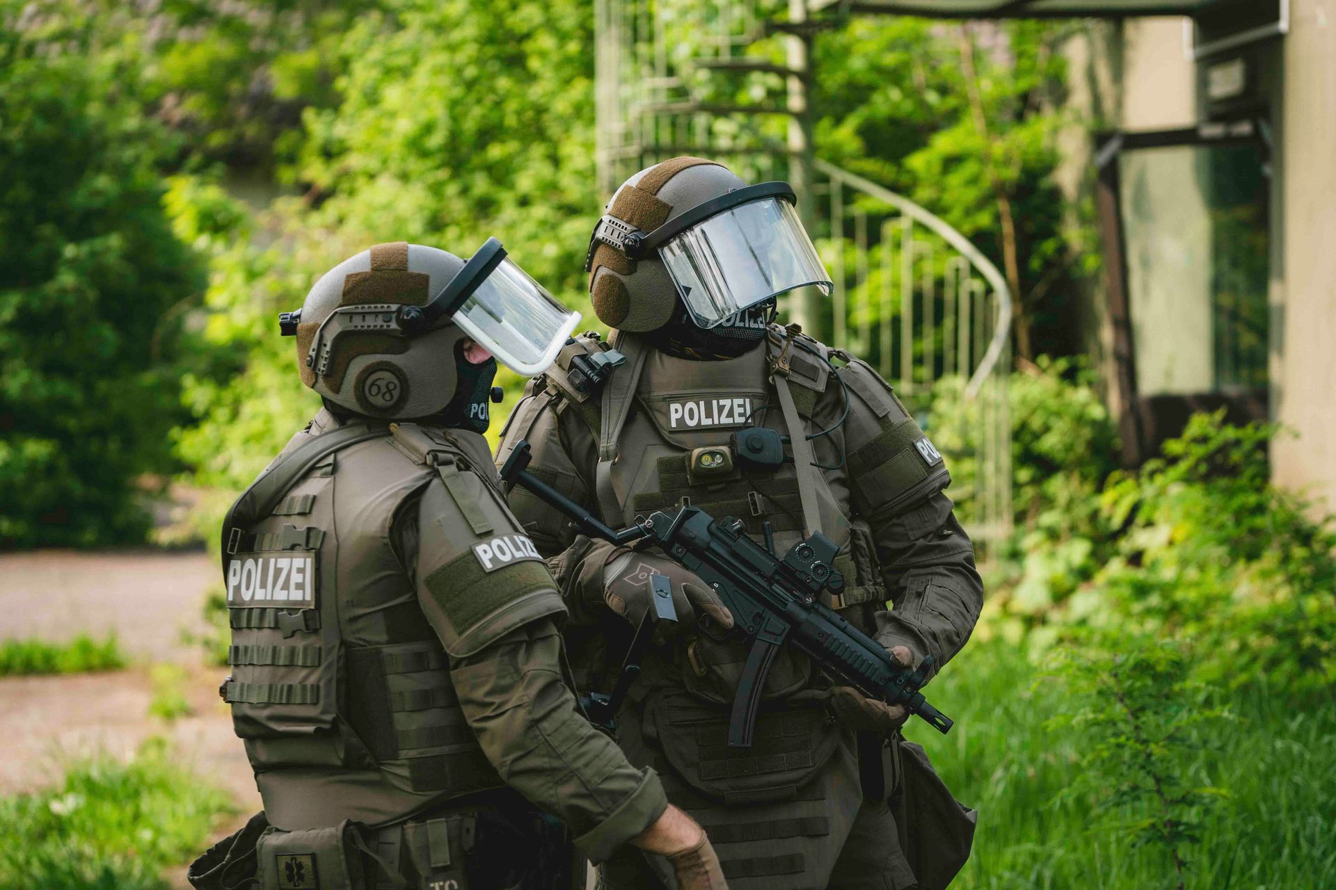 Zwei Polizisten in taktischer Ausrüstung im Freien, einer von ihnen hält eine Maschinenpistole