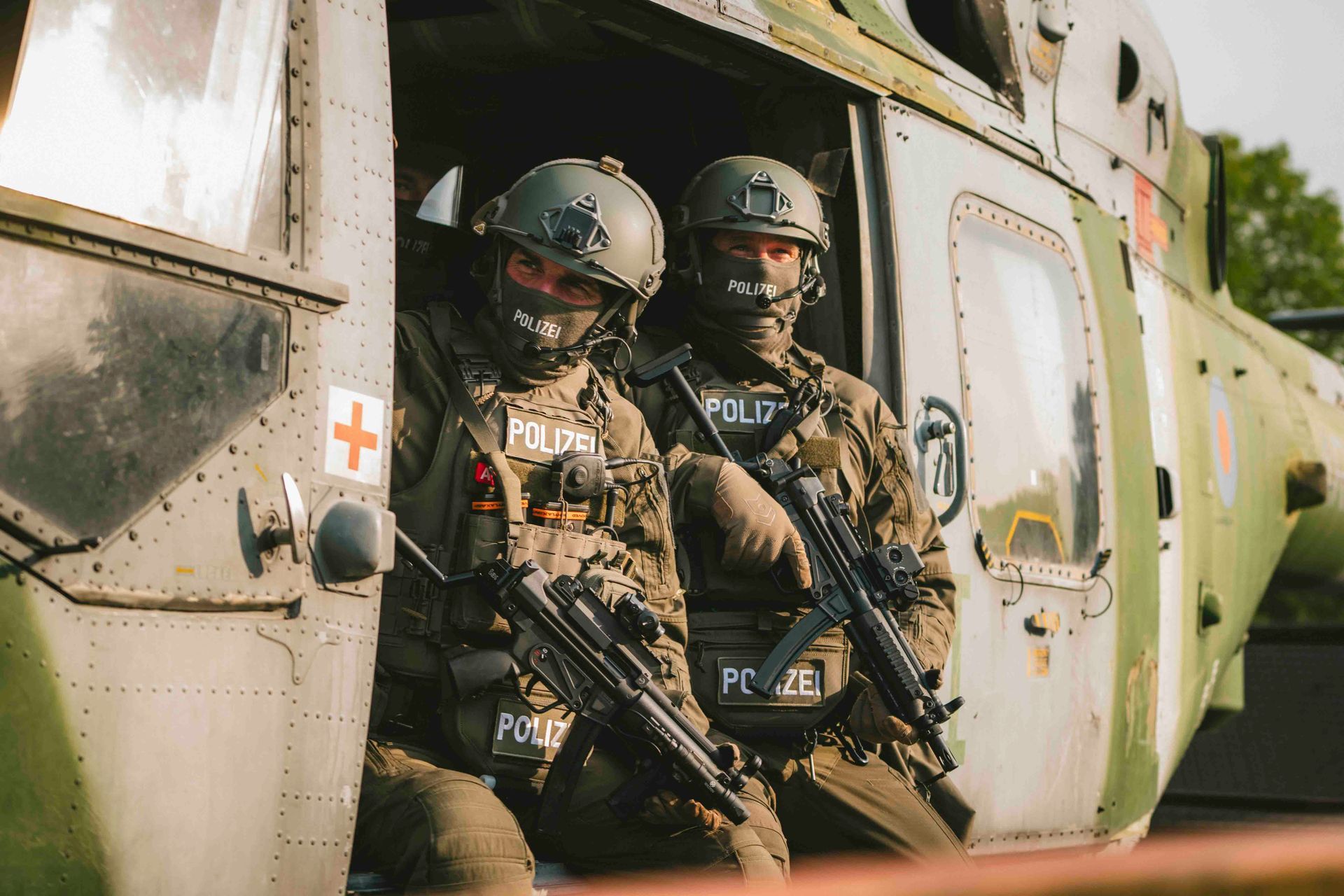 Zwei bewaffnete Polizisten in Tarnkleidung verlassen einen Hubschrauber.