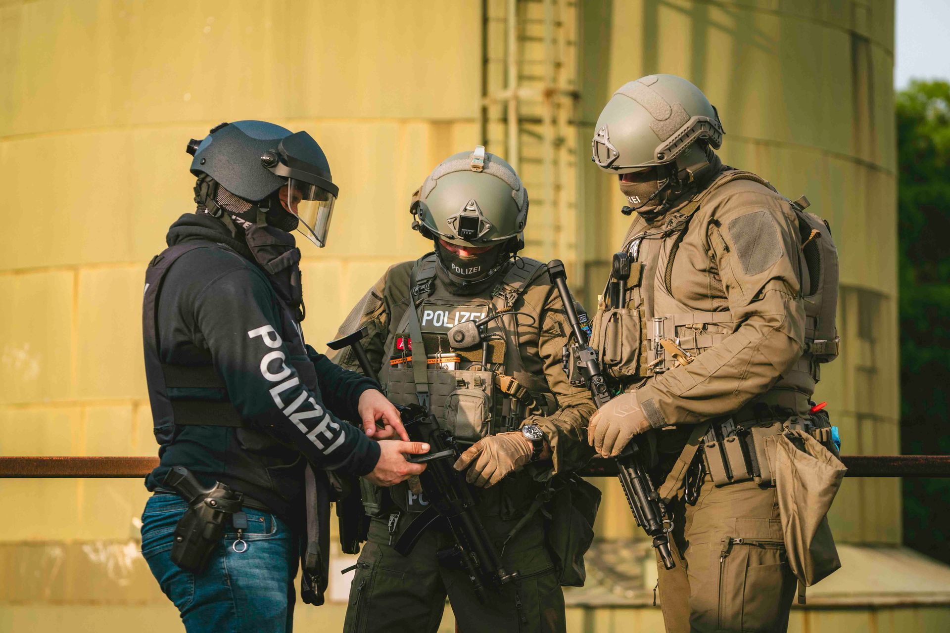 Drei bewaffnete Polizisten in taktischer Ausrüstung inspizieren Ausrüstung auf einem Dach.