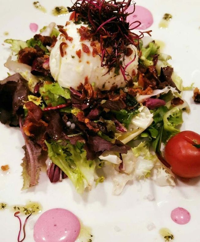 Un plato blanco cubierto con una ensalada y un tomate.