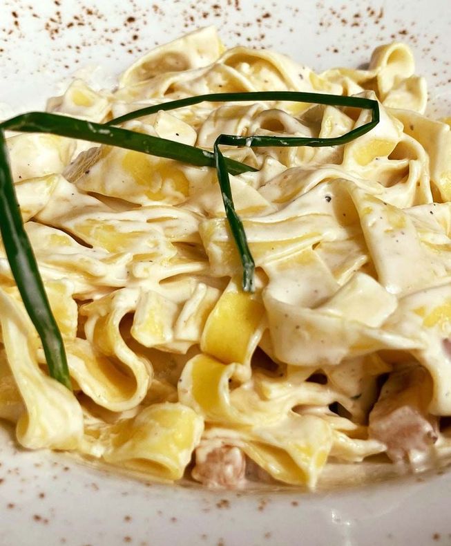 Un primer plano de un plato de pasta con salsa y cebollas verdes.