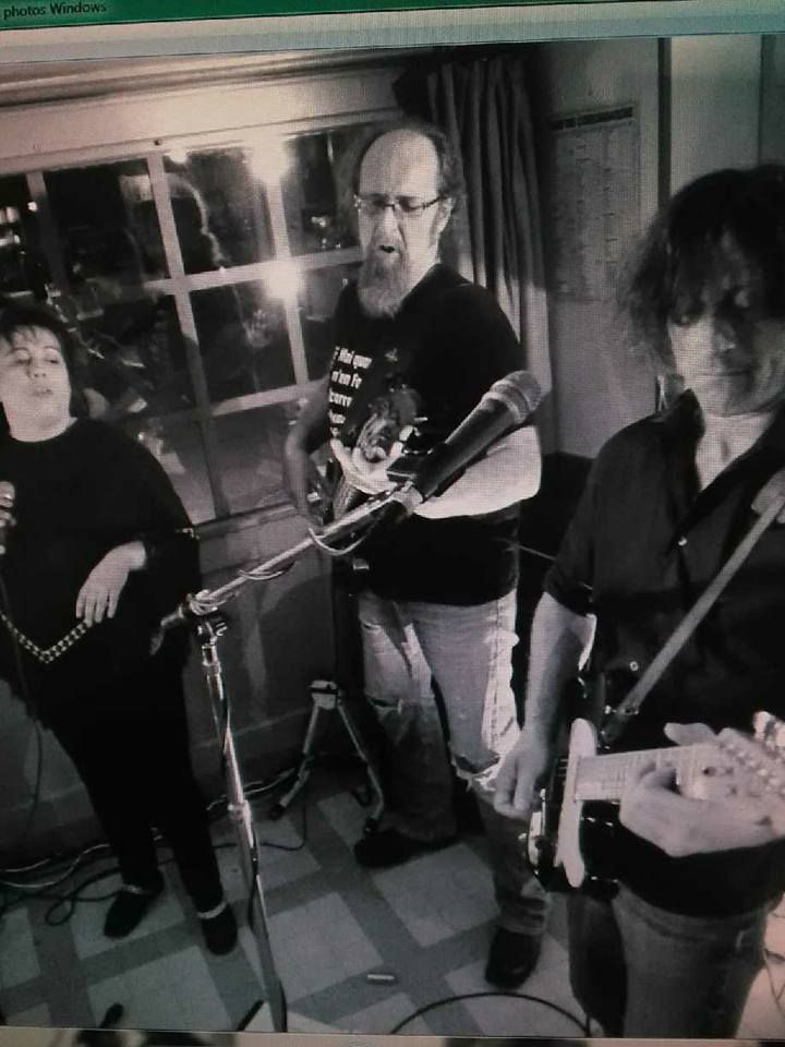 Trois personnes en train de chanter et de jouer de la guitare.