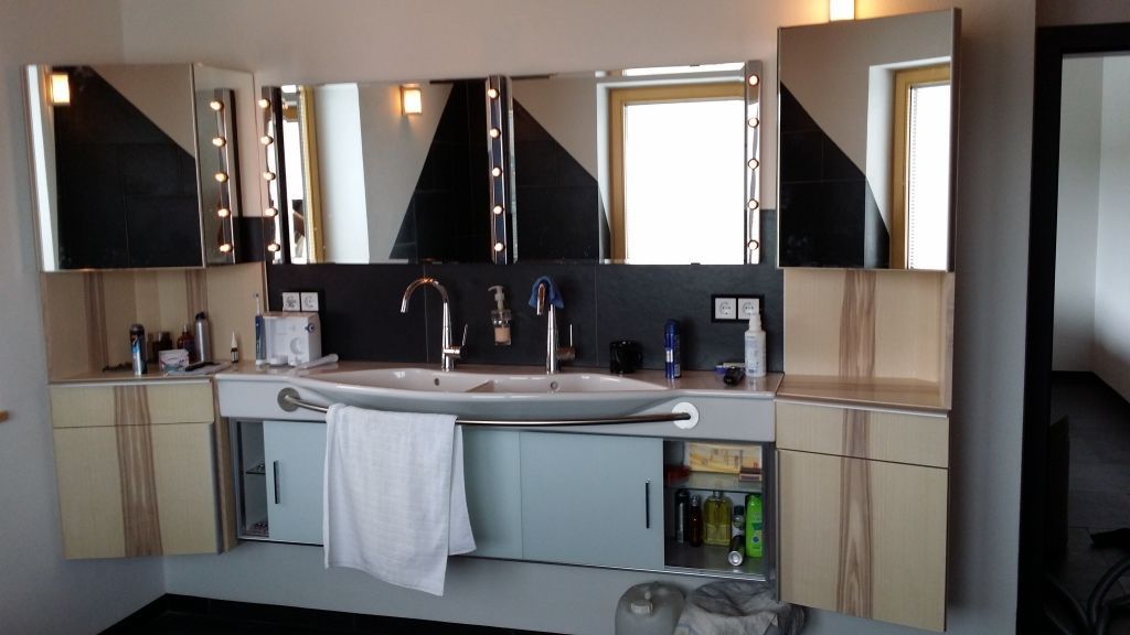 Waschbeckenbereich mit mehreren Spiegeln und kleinen Schränken unterhalb