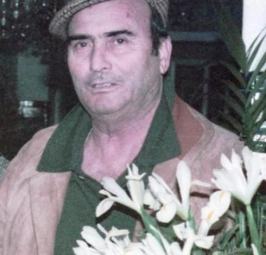 Un hombre con sombrero sostiene un ramo de flores blancas.