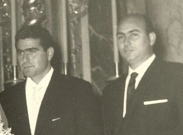 Dos hombres con traje y corbata están parados uno al lado del otro en una fotografía en blanco y negro.