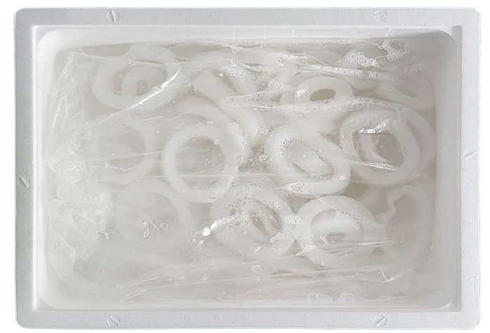 Un recipiente de plástico lleno de cebollas en rodajas dentro de una bolsa de plástico.