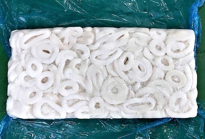 Un bloque de aros de cebolla congelados está envuelto en plástico.