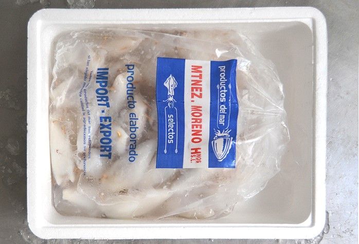 Una pila de calamares congelados en un recipiente de plástico.