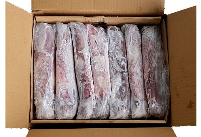 Una caja de cartón llena de carne congelada sobre un fondo blanco.