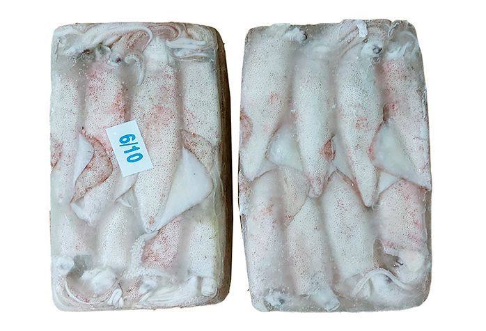 Una caja de calamares congelados reposa encima de un palé de madera.