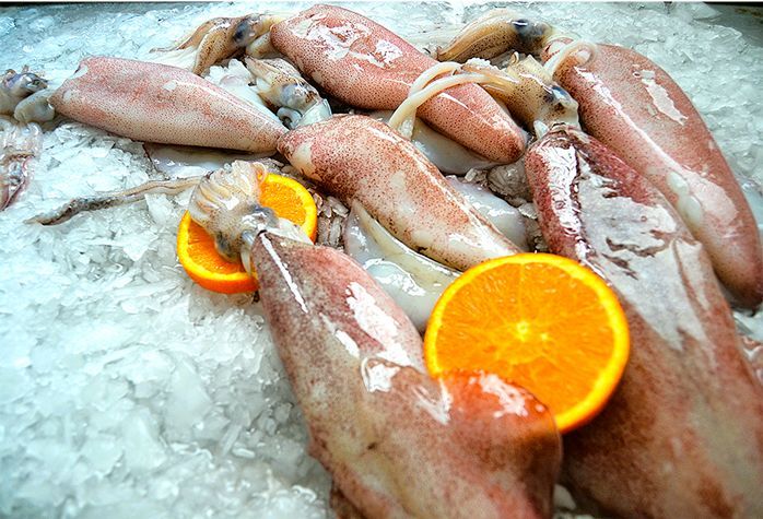 Un montón de calamares y naranjas en hielo.