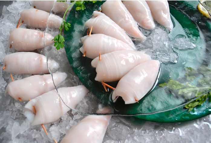 Un montón de calamares están sentados sobre hielo en un plato verde.