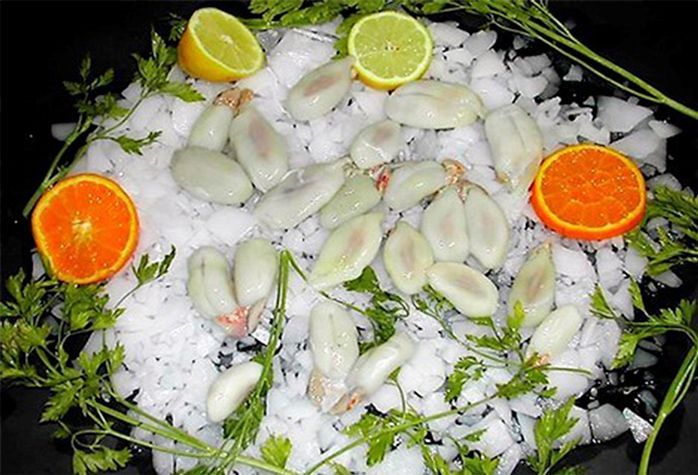 Un plato de comida con camarones, limones y naranjas en hielo.
