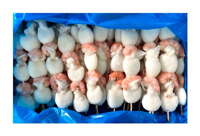 Una bolsa azul llena de camarones y calamares en brochetas.