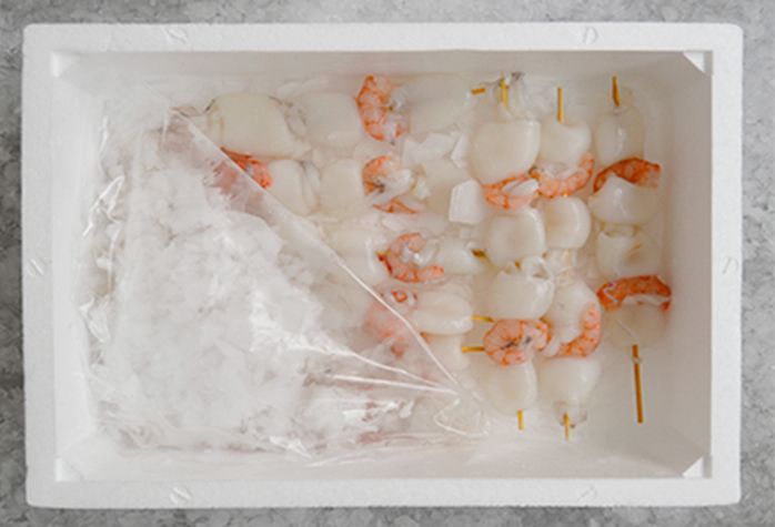 Una caja llena de camarones y hielo sobre una mesa.