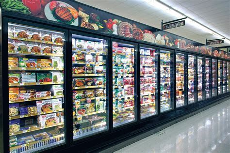 Una fila de estantes refrigerados en una tienda de comestibles llenos de gran cantidad de alimentos.
